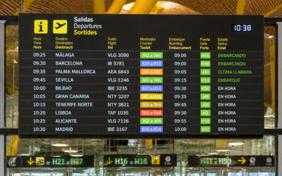 Panel de información de salidas en un aeropuerto español con varias aerolíneas y horarios de vuelo visibles