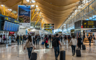 Interior de una terminal aeroportuaria moderna y concurrida en España, con viajeros y luz natural