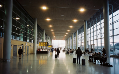 Interior de la terminal del aeropuerto de Santiago con viajeros y señalética de destinos internacionales