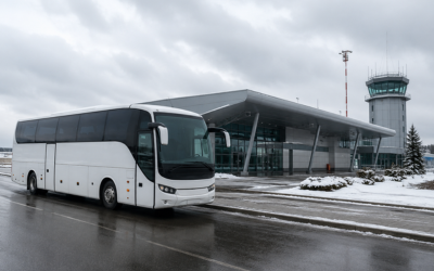 Autobús de largo recorrido estacionado frente a una terminal de aeropuerto pequeña en Polonia, ambiente invernal con cielo nublado