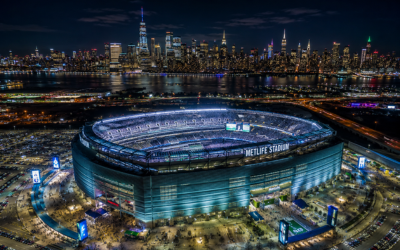 vuelos baratos Nueva York Mundial 2026 - Vista aérea del MetLife Stadium de Nueva Jersey de noche durante un gran evento deportivo, con el skyline de Manhattan iluminado al fondo