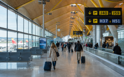 Sala de embarque de aeropuerto español moderno con viajeros caminando, luz natural, fotografía editorial