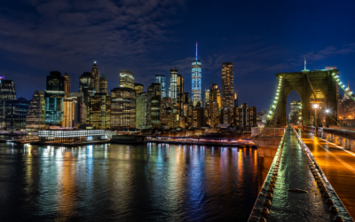 Skyline nocturno de Manhattan visto desde el puente de Brooklyn, con luces reflejadas en el río East River, fotografía profesional de viajes